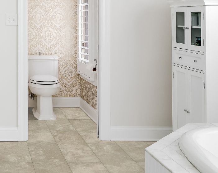 toilet in a stylish bathroom with tile floors and patterned wallpaper