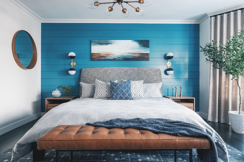 Bright blue accent wall behind bed in bedroom by designer Louis Duncan-He