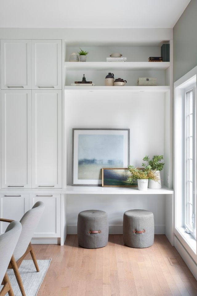 Built-in storage nook in living room with artwork, greenery, and cushioned seating