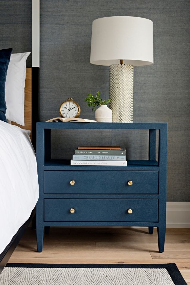 Navy blue nightstand in bedroom with gray walls and rugs 
