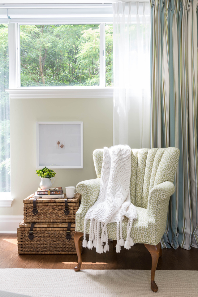 Green accent chair in living room with cozy blanket 