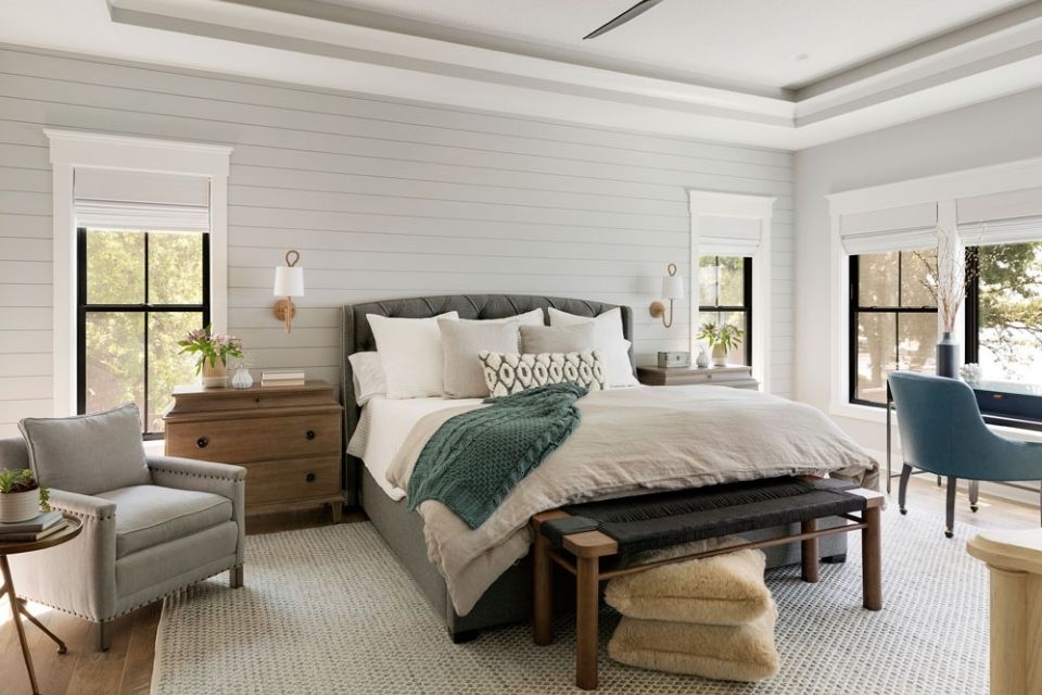 Large cozy bedroom in lake house with seating area and shiplap walls