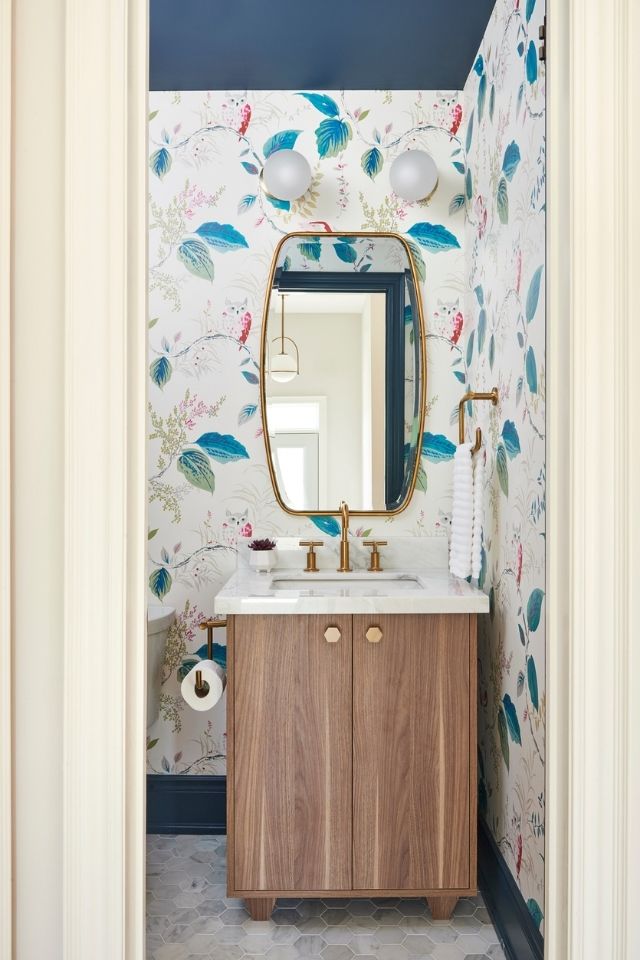 Bold wallpaper in bathroom with wood vanity and gold accents 
