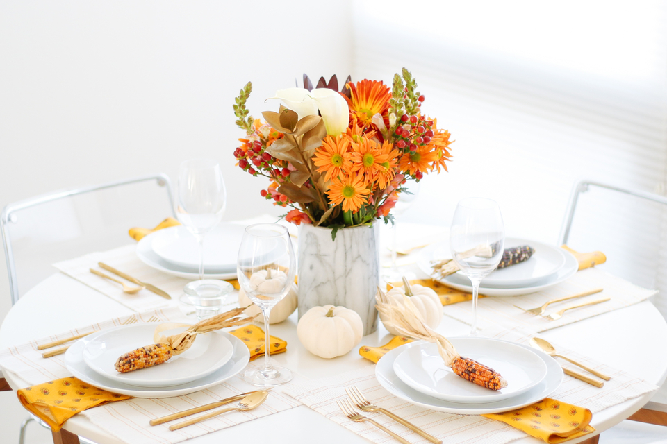 Fall holiday table with orange flowers and corn husks 