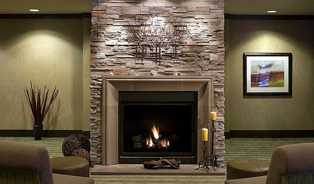 natural stone fireplace in a cozy room with green textured carpet Photo: Home Designing