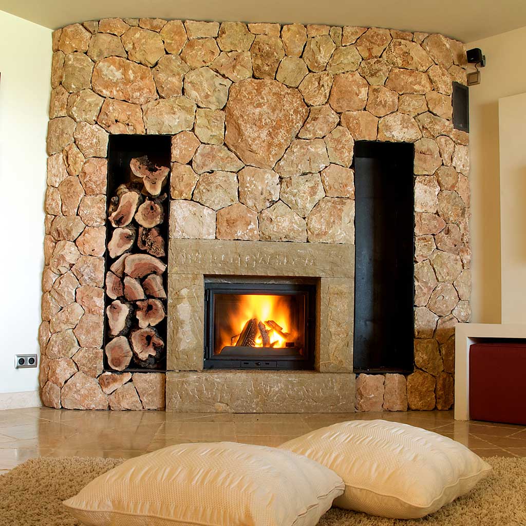 large stone fireplace with built-in wood storage warms a tile floor Photo: Gel Fireplaces