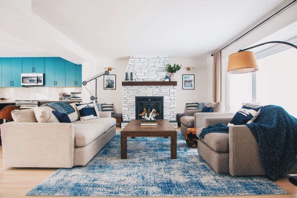 Living room design with white stone fireplace and blue rug 