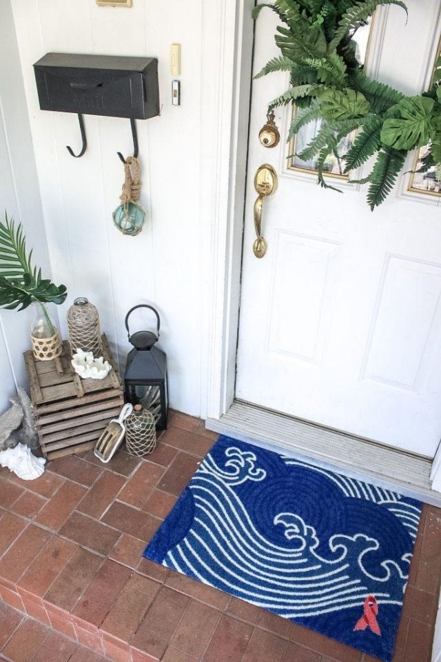 Close up of beachy welcome mat on brick front porch area 