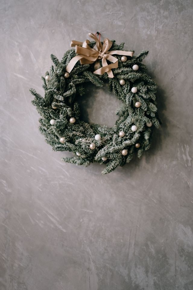 Green Christmas wreath with beige colored bow and ornaments 