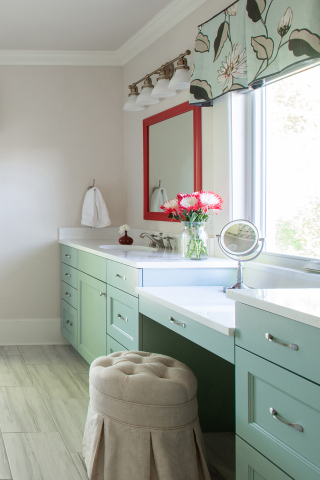 Mint bathroom vanity in remodeled bathroom with red accents and wallpaper 
