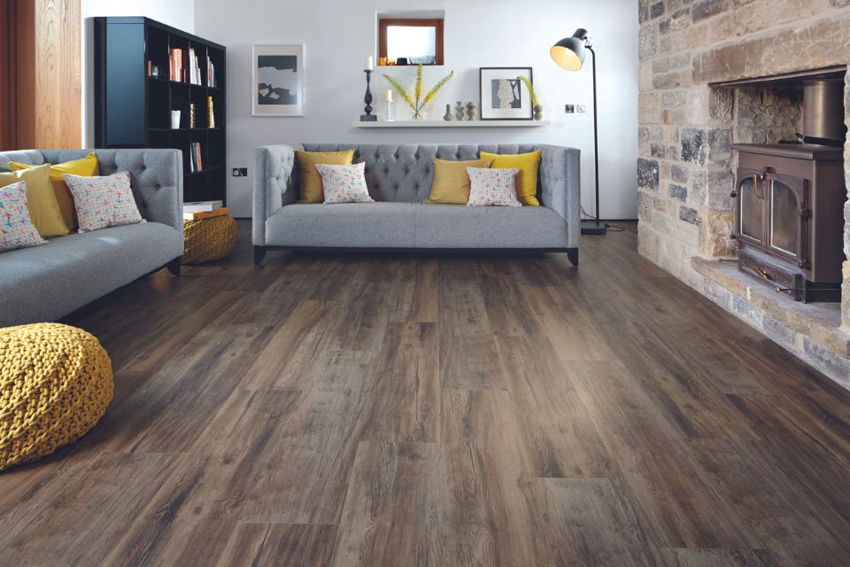 Rustic wood-look flooring in living room with gray sofas and yellow accents