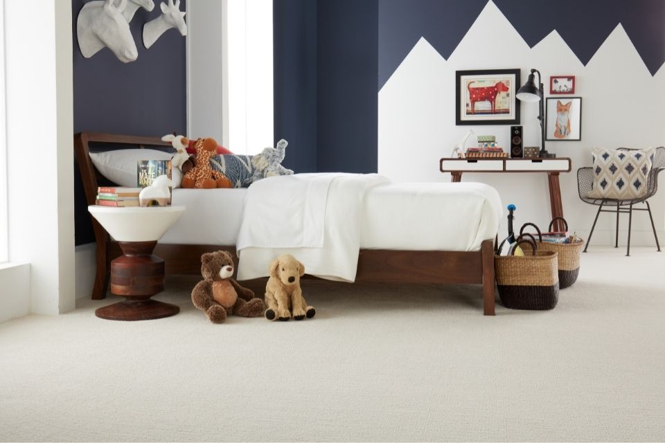fun kids bedroom with mountain accent wall and soft beige carpet