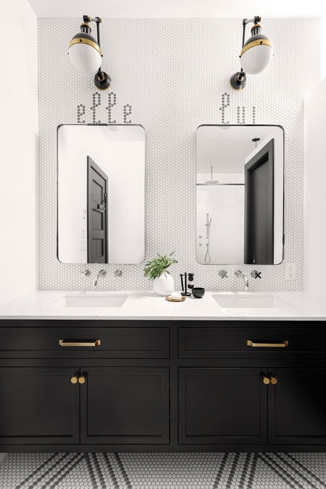 Black and white bathroom with black vanity, custom tile, and sconces