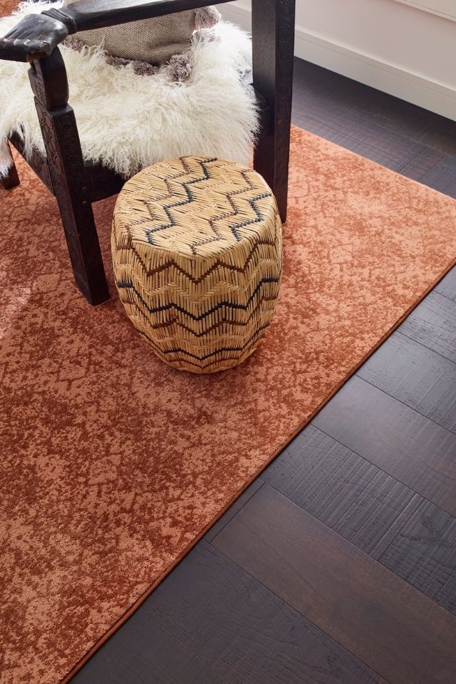 rust colored patterned area rug on dark hardwood flooring