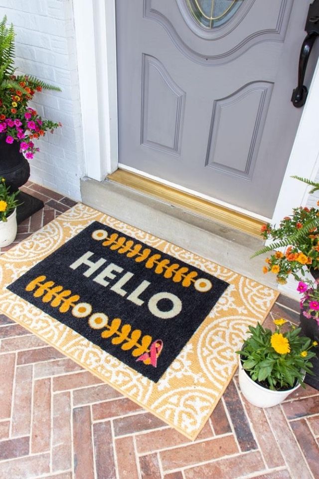 Close up of yellow layered hello welcome mat and gray door