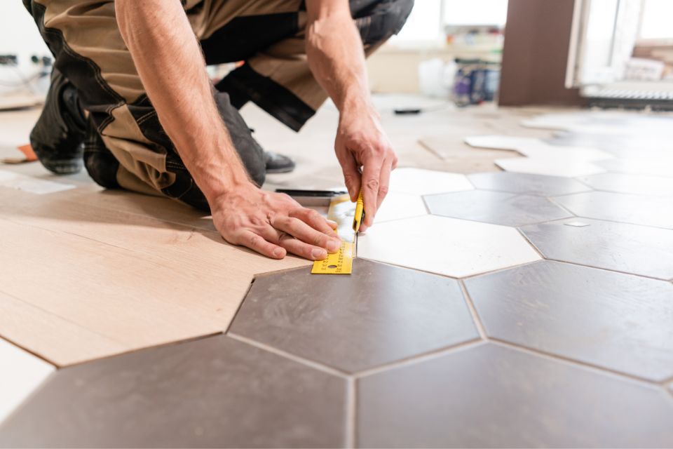 flooring installer installing tile in home being renovated 