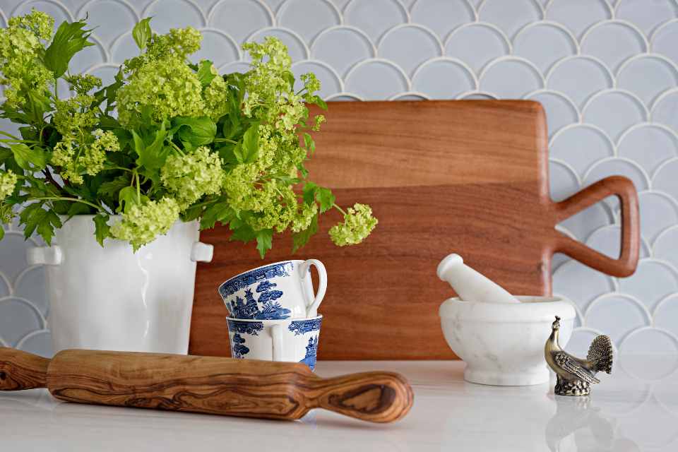 kitchen counter with blue mosaic tile backsplash, china tea cups and wooden roller
