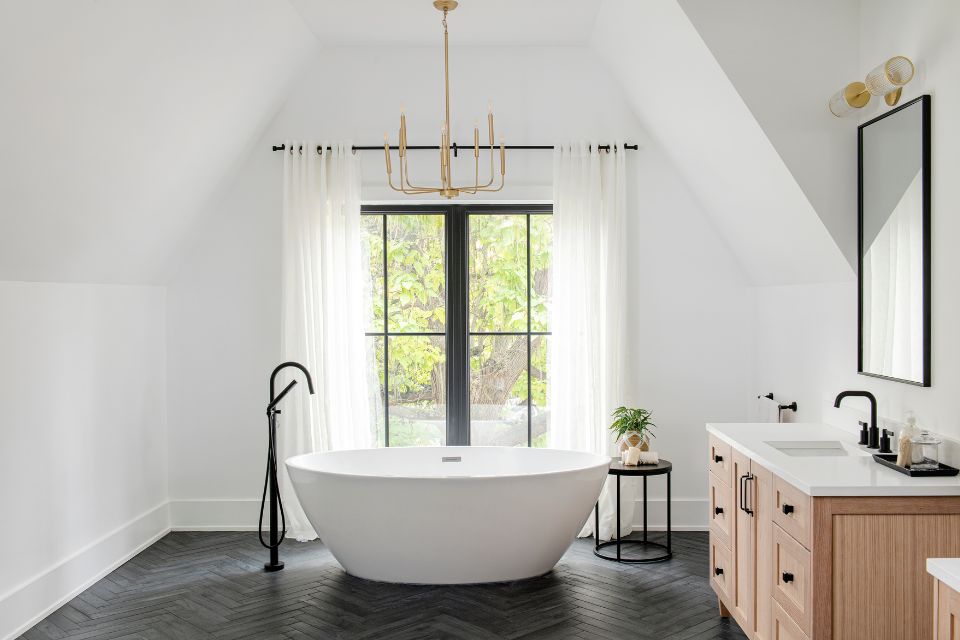 deep soak tub in designer bathroom with dark herringbone floors